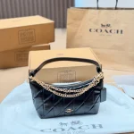 This underarm bag features shiny cowhide leather, in a classic black colorway with a metal chain-box - Image 10