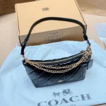 This underarm bag features shiny cowhide leather, in a classic black colorway with a metal chain-box - Image 9