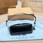 This underarm bag features shiny cowhide leather, in a classic black colorway with a metal chain-box - Image 6