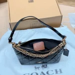 This underarm bag features shiny cowhide leather, in a classic black colorway with a metal chain-box - Image 3
