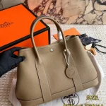 Garden Bag in premium Togo cowhide, incredibly soft to the touch. Features steel hardware, hand-stitched wrist strap, and authentic original lining-box