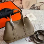 "Garden bag crafted from full-grain Togo cowhide, featuring a soft texture. Equipped with steel hardware, hand-stitched wrist strap, and original lining-box
