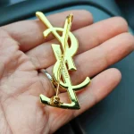 YSL Gold tone Cassandre Metal Brooch, Vintage Twisted Logo Pin, Blazer & Coat Accessory - Image 9